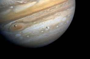 moons Io and Europa with Jupiter's Great Red Spot behind them